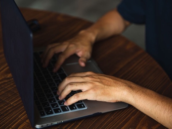 A person typing on a laptop, representing a contact and enquiry form